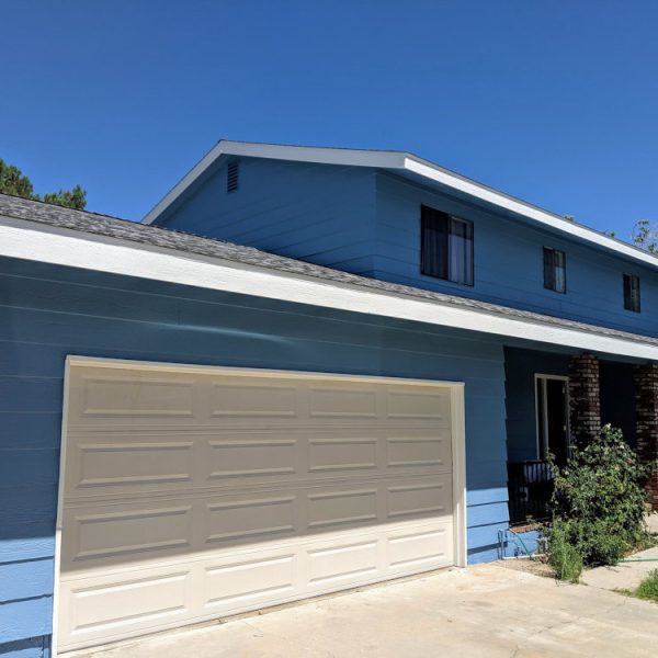 Full front elevation of a two-story home in Santa Clarita freshly painted with a vibrant blue body and crisp white trim on the fascia and roofline by Paint Daddy.