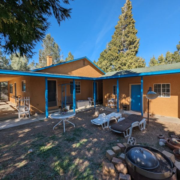 A full view of a finished Spanish-style ranch house in Leona Valley, CA, featuring a vibrant orange stucco body and custom turquoise architectural trim, completed by Paint Daddy.