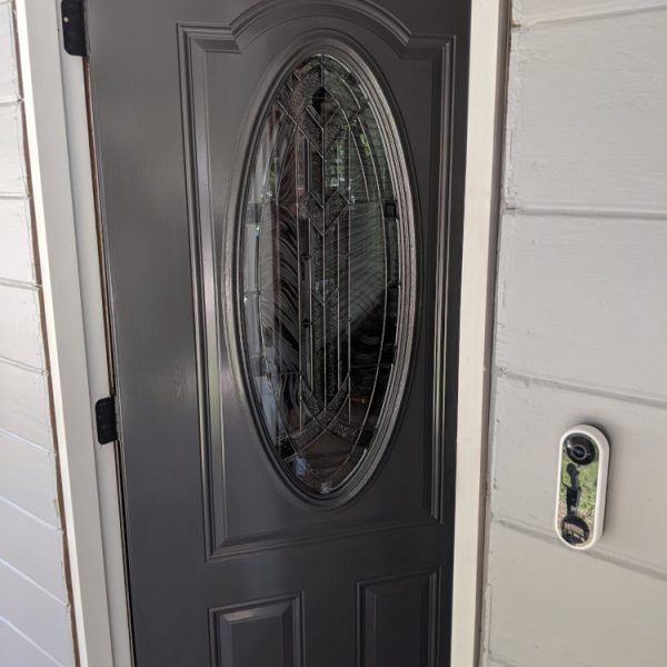 A professional semi-gloss charcoal refinishing of an ornate entry door with a large beveled glass oval insert by Paint Daddy.