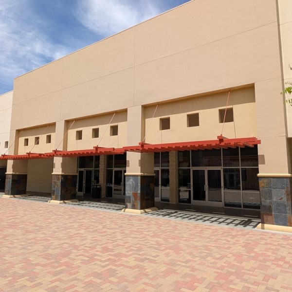 A wide shot of the main entrance of Desert Vineyard Church in Lancaster, CA, featuring new exterior painting on stucco surfaces and wrought iron overhangs, completed by Paint Daddy