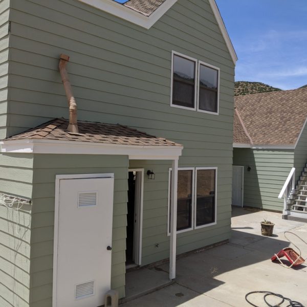 Side view of a detached garage and guest unit painted in sage green with a crisp white exterior staircase and trim by Paint Daddy.