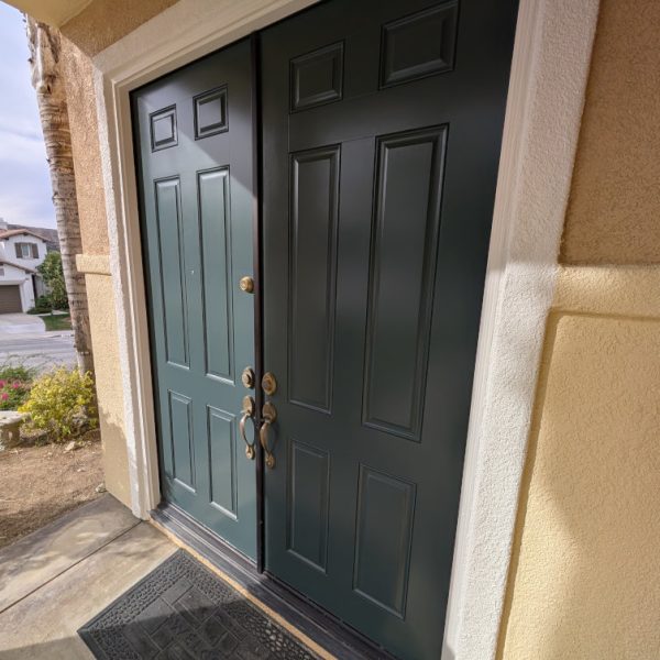 Professional refinishing of double front doors in a deep forest green, featuring crisp white trim and smooth stucco integration by Paint Daddy in Santa Clarita.