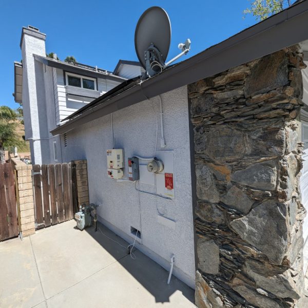 Side profile of a Lancaster home showing precision painting around electrical meters, conduit, and utility boxes with clean grey fascia lines, by Paint Daddy.