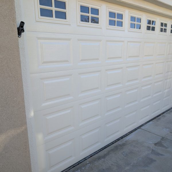 Close-up view of a freshly painted white garage door with decorative windows, showcasing smooth coverage and clean trim lines by Paint Daddy in Santa Clarita.