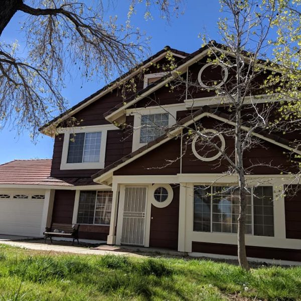 Full view of a historic Victorian home in Santa Clarita, CA, featuring freshly painted chocolate brown lap siding and extensive intricate white fretwork, corbels, and porches, completed in a specialized velvet low-luster finish by Paint Daddy.