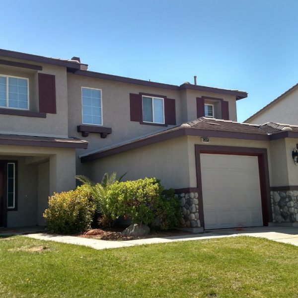 A freshly painted two-story home in Lancaster, CA, featuring warm taupe stucco and deep burgundy shutters and trim by Paint Daddy.