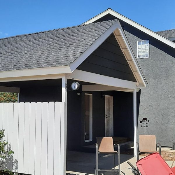 Side view of a two-story home and carport featuring uniform charcoal stucco and sharp white fascia and window trim by Paint Daddy.