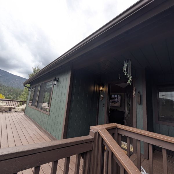 Finished entryway and large wooden deck of a Pine Mountain Club cabin, showcasing a cohesive green and brown solid body stain scheme by Paint Daddy.
