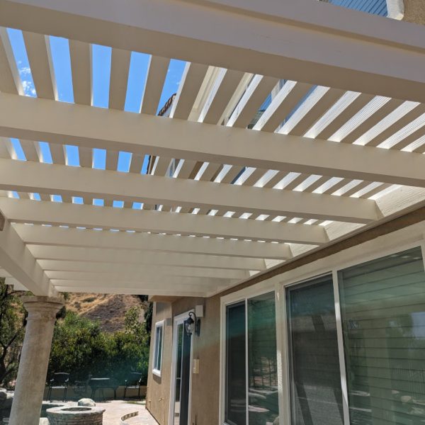 Detailed view looking up at a freshly painted backyard pergola with clean white rafters against a bright blue sky, completed with high-precision detail by Paint Daddy in Santa Clarita.