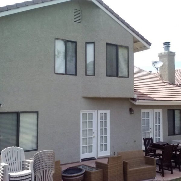 Rear view of a finished residential repaint in Santa Clarita showing freshly painted white French doors and window trim against a clean stucco exterior, by Paint Daddy.