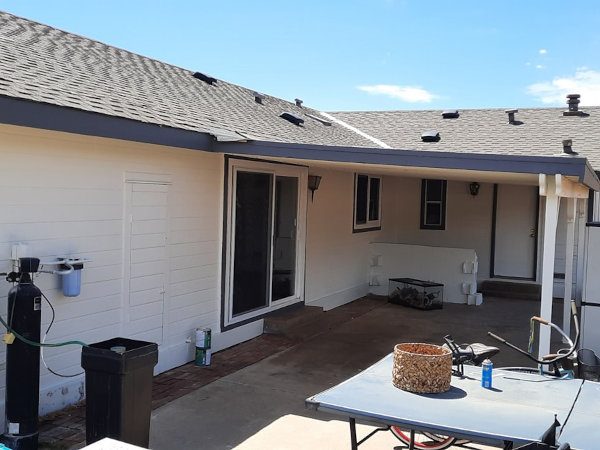 Rear patio view of an Action residence featuring freshly painted white lap siding, slate grey fascia, and white-out utility doors by Paint Daddy.