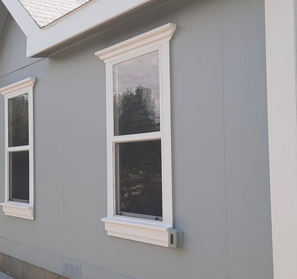 Side profile of a home featuring light slate grey smooth siding, a steel blue accent wall, and thick brilliant white window casings by Paint Daddy.