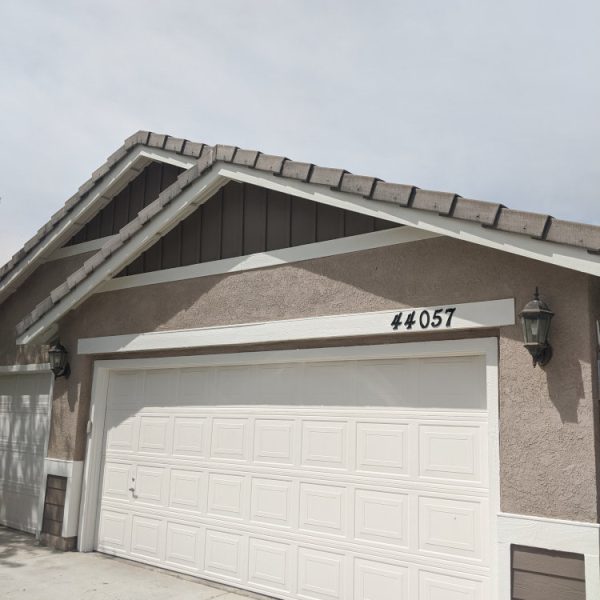Front view of a home featuring sandy tan stucco, cocoa brown gables, and thick white trim and porch columns by Paint Daddy.