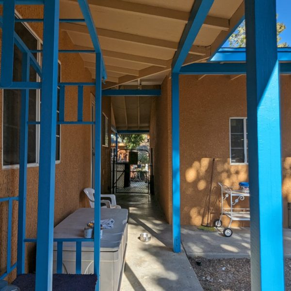 A detailed view of a freshly painted patio in Leona Valley, showing crisp lines between turquoise columns/arches and the vibrant orange stucco walls, by Paint Daddy.