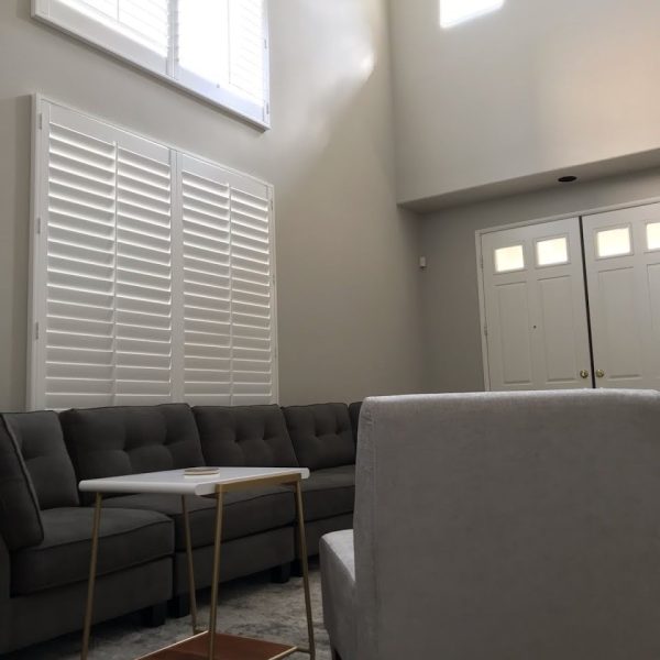 A grand Valencia living room featuring soaring greige walls, brilliant white plantation shutters, and matching double-entry doors by Paint Daddy.