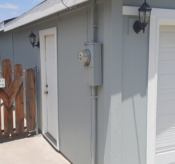 Rear side view of a house featuring a white garage door, white entry door, and light slate grey siding with color-matched utility hardware by Paint Daddy.